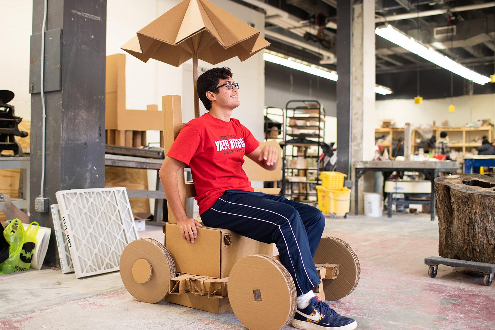 Jeremy Vega poses with his cardboard chair